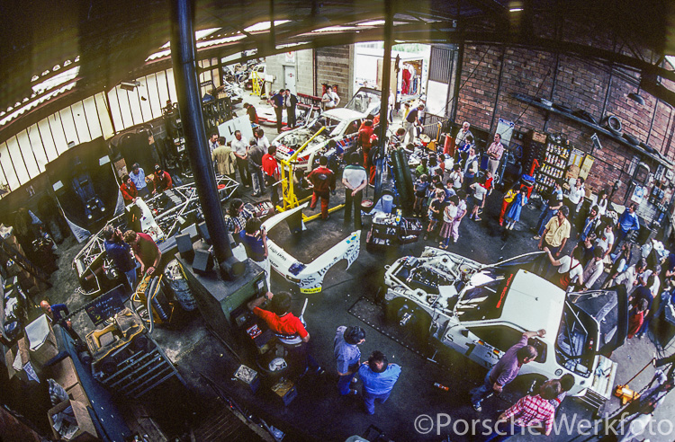 In a rather crowded Teloché workshop, mechanics try to work on a Porsche 936/81, 924 GTP Le Mans and 924 Carrera GTR